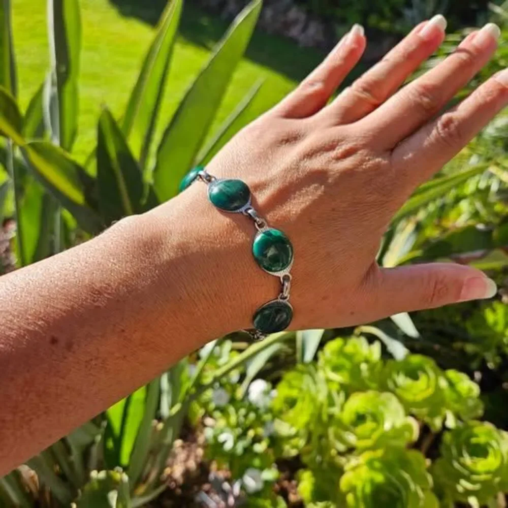 Malachite bracelet features natural green gemstones set in a silver colored link
